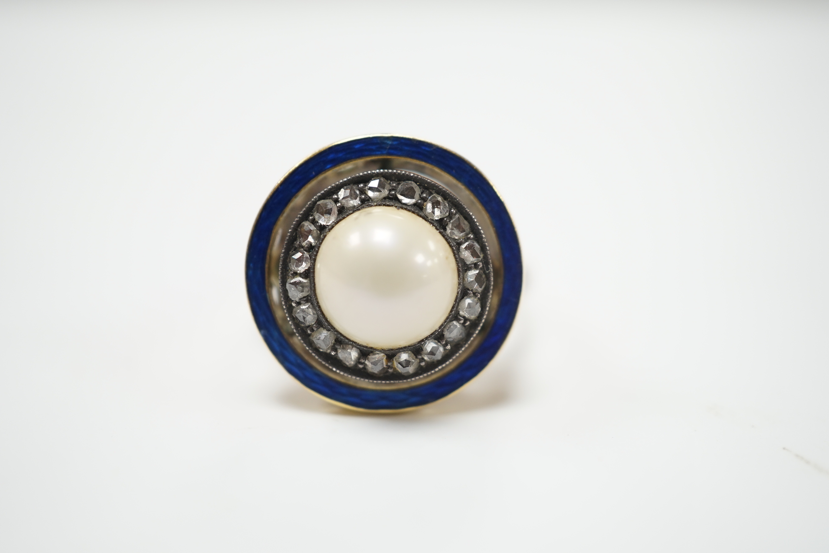 An early to mid 20th century yellow metal, split pearl, rose cut diamond chip and blue enamel set target ring, size H, ross weight 4.6 grams.